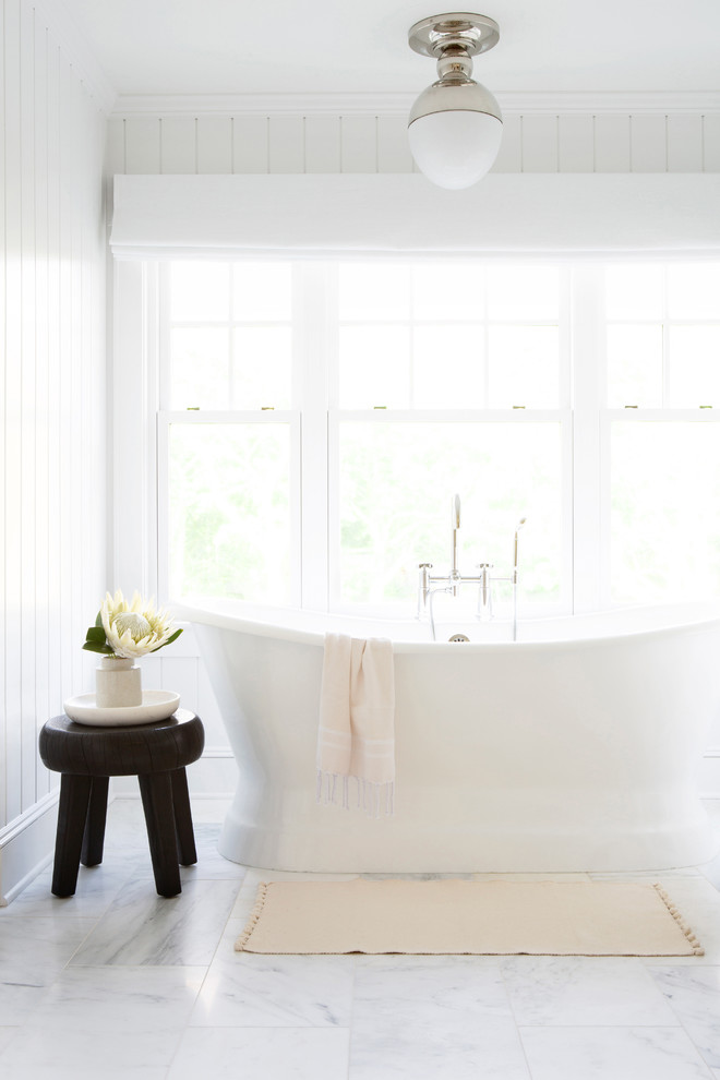 Idéer för ett mellanstort maritimt vit en-suite badrum, med möbel-liknande, vita skåp, ett fristående badkar, en toalettstol med hel cisternkåpa, vita väggar, marmorgolv, ett undermonterad handfat, marmorbänkskiva och vitt golv