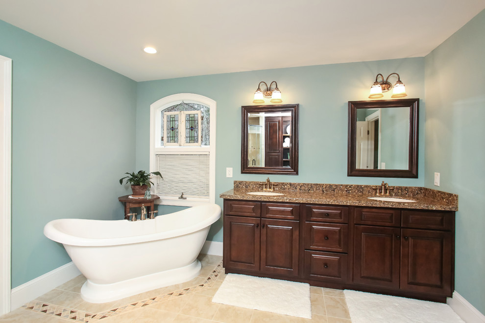Idee per una stanza da bagno padronale classica di medie dimensioni con ante con bugna sagomata, ante in legno bruno, vasca freestanding, pareti blu, pavimento con piastrelle in ceramica e lavabo sottopiano