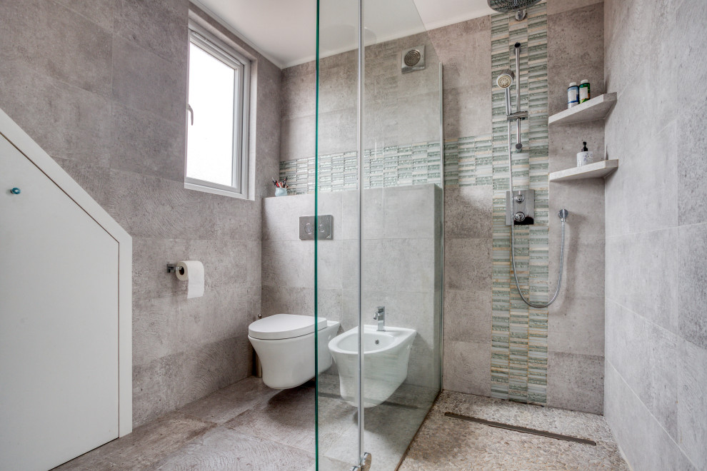 This is an example of a medium sized contemporary shower room bathroom in London with a built-in shower, a wall mounted toilet, grey tiles, grey floors and a sliding door.