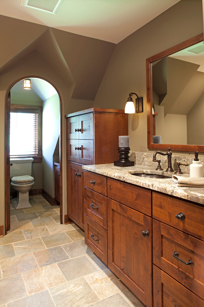 Foto de cuarto de baño campestre grande con lavabo bajoencimera, puertas de armario de madera oscura y armarios con paneles empotrados