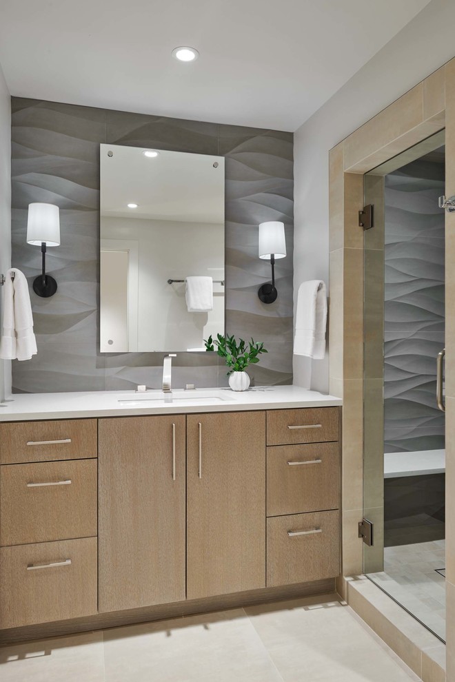 Пример оригинального дизайна: ванная комната среднего размера в стиле модернизм с плоскими фасадами, светлыми деревянными фасадами, серой плиткой, столешницей из искусственного кварца, белой столешницей, серыми стенами, полом из керамогранита, накладной раковиной и бежевым полом