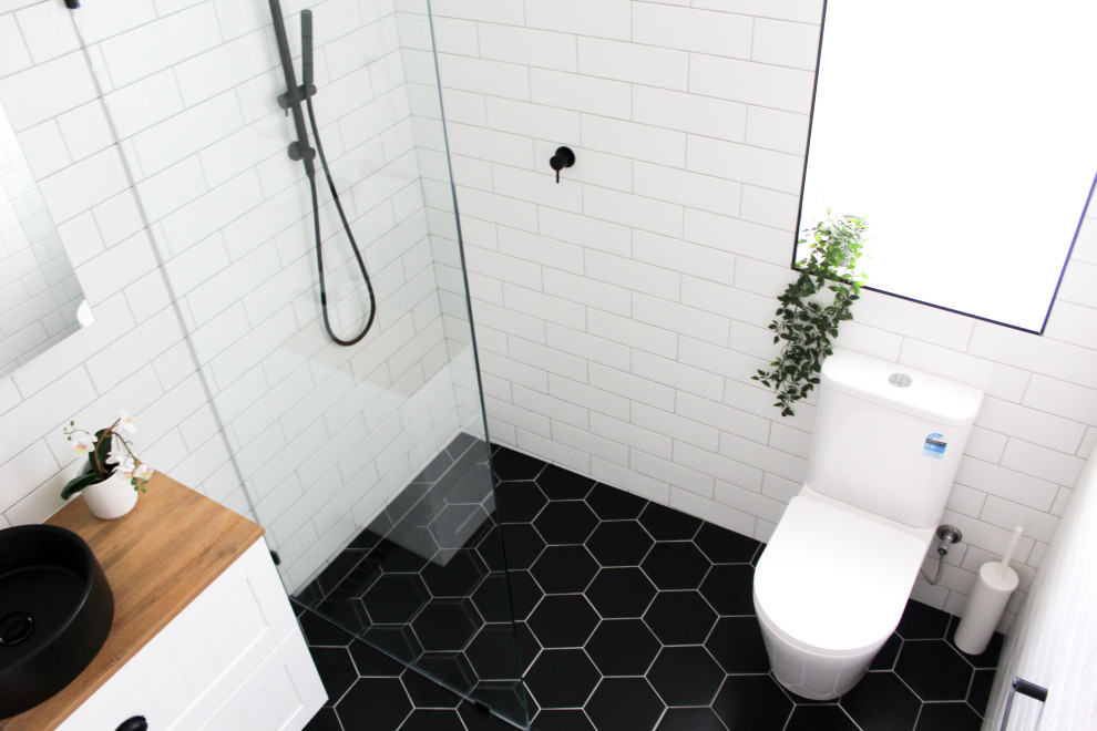 Bathroom - small modern kids' white tile and ceramic tile porcelain tile, black floor, single-sink and brick wall bathroom idea in Perth with shaker cabinets, white cabinets, a one-piece toilet, white walls, a vessel sink, wood countertops, beige countertops and a floating vanity