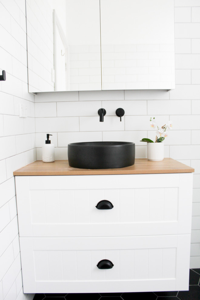 Inspiration for a small modern family bathroom in Perth with shaker cabinets, white cabinets, a walk-in shower, a one-piece toilet, white tiles, ceramic tiles, white walls, porcelain flooring, a vessel sink, wooden worktops, black floors, an open shower, beige worktops, a single sink, a floating vanity unit and brick walls.