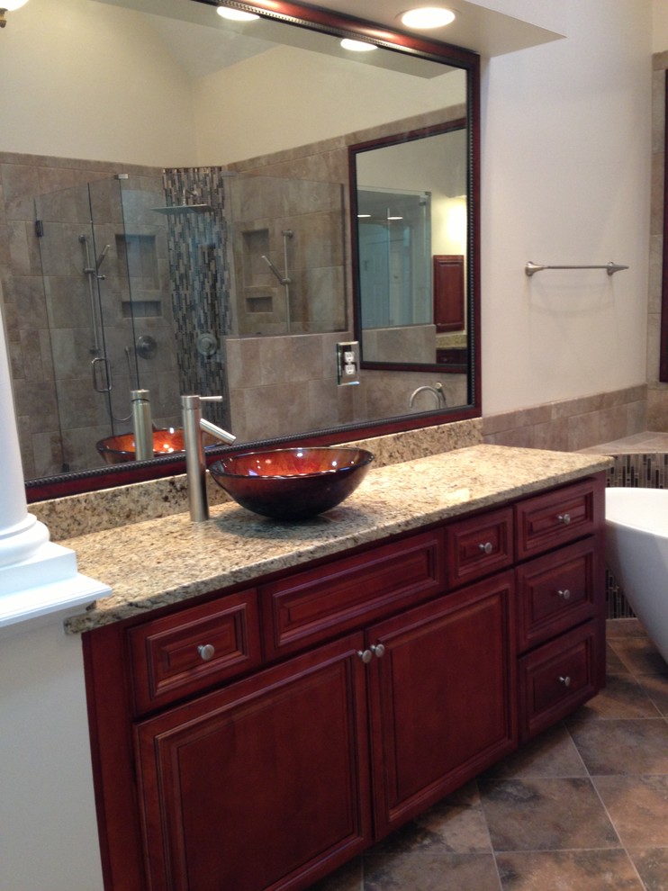 Bathroom - large transitional master brown tile and stone slab porcelain tile bathroom idea in Raleigh with a vessel sink, raised-panel cabinets, medium tone wood cabinets, granite countertops, a two-piece toilet and black walls