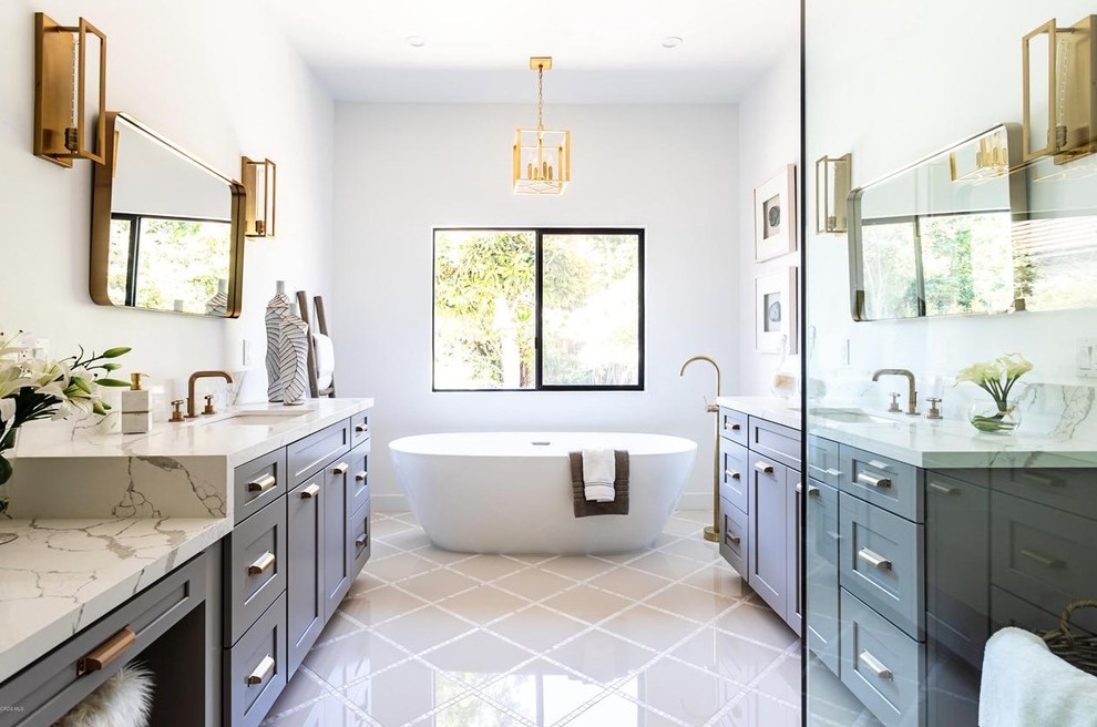 Landhaus Badezimmer En Suite mit Schrankfronten im Shaker-Stil, grauen Schränken, freistehender Badewanne, weißer Wandfarbe, Unterbauwaschbecken, weißem Boden und beiger Waschtischplatte in Los Angeles