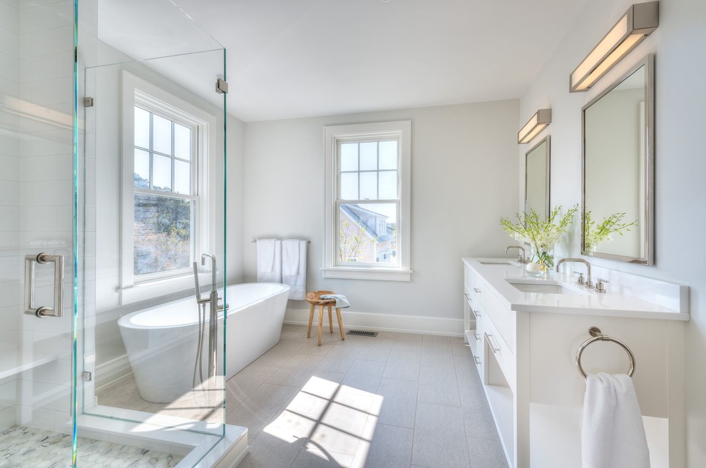 Mid-sized beach style 3/4 porcelain tile porcelain tile and gray floor bathroom photo in Providence with recessed-panel cabinets, white cabinets, white walls, an undermount sink, solid surface countertops and a hinged shower door