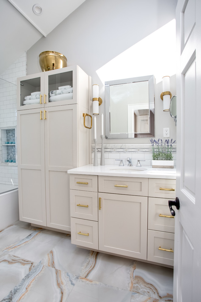 Идея дизайна: главная ванная комната в стиле неоклассика (современная классика) с фасадами в стиле шейкер, серыми фасадами, ванной в нише, душем над ванной, раздельным унитазом, белой плиткой, плиткой кабанчик, серыми стенами, полом из керамогранита, врезной раковиной, столешницей из искусственного кварца, разноцветным полом, душем с распашными дверями и белой столешницей
