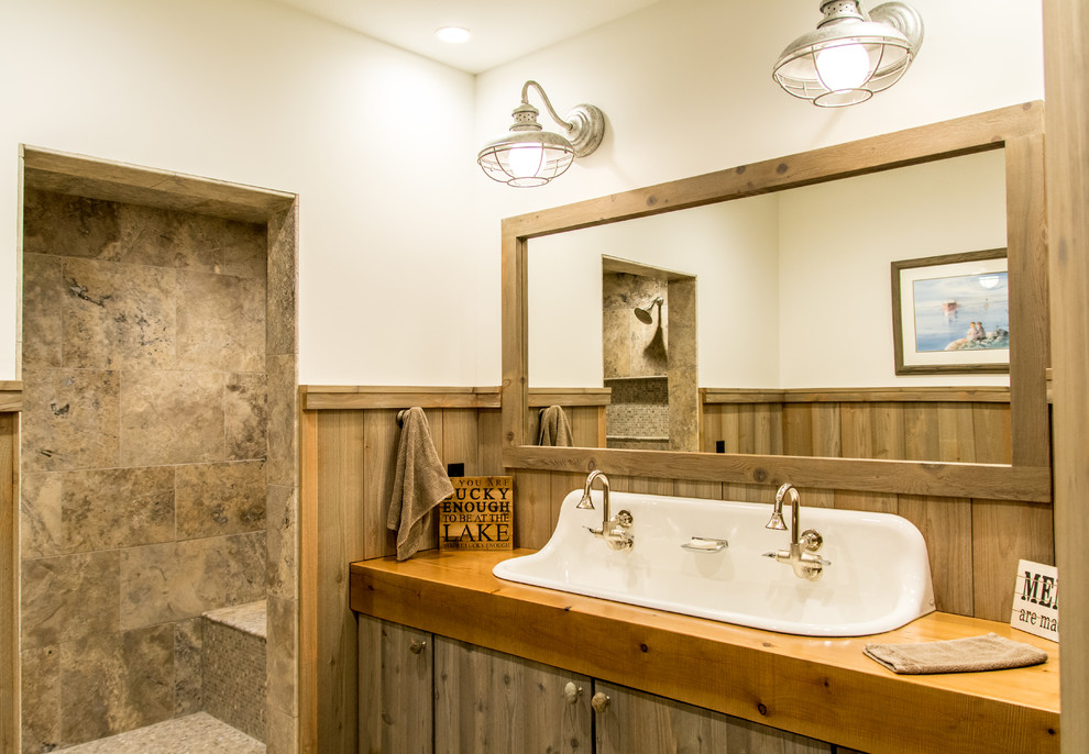 Example of a mountain style brown tile bathroom design in Other with flat-panel cabinets, medium tone wood cabinets, white walls, a trough sink, wood countertops and brown countertops