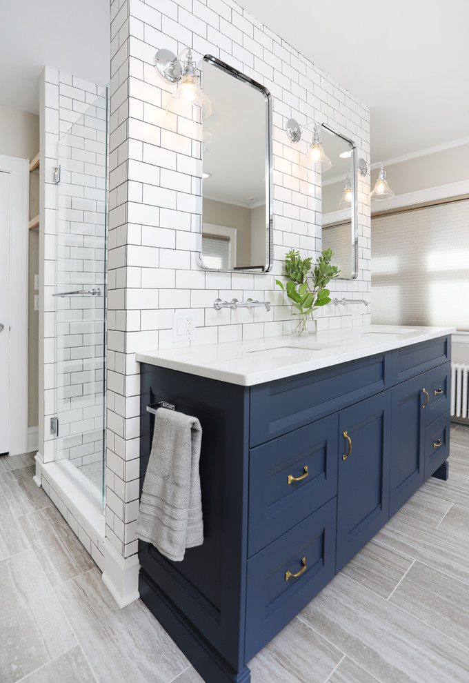 Idéer för att renovera ett mellanstort vintage vit vitt en-suite badrum, med luckor med infälld panel, blå skåp, vit kakel, keramikplattor, beige väggar, klinkergolv i porslin, ett undermonterad handfat, bänkskiva i kvarts, en dusch i en alkov, grått golv och dusch med gångjärnsdörr