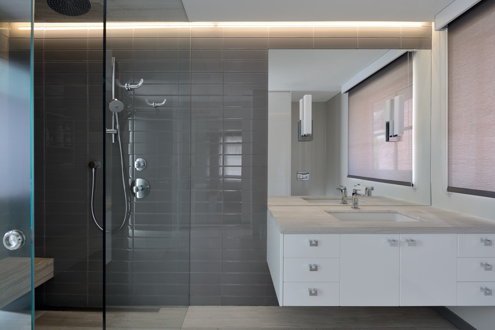 На фото: большая ванная комната в современном стиле с белыми фасадами, серой плиткой и стеклянной плиткой