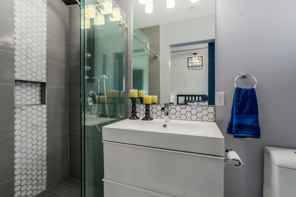 Exempel på ett litet modernt en-suite badrum, med ett avlångt handfat, möbel-liknande, vita skåp, bänkskiva i akrylsten, en kantlös dusch, en toalettstol med separat cisternkåpa, grå kakel, porslinskakel, grå väggar och klinkergolv i porslin