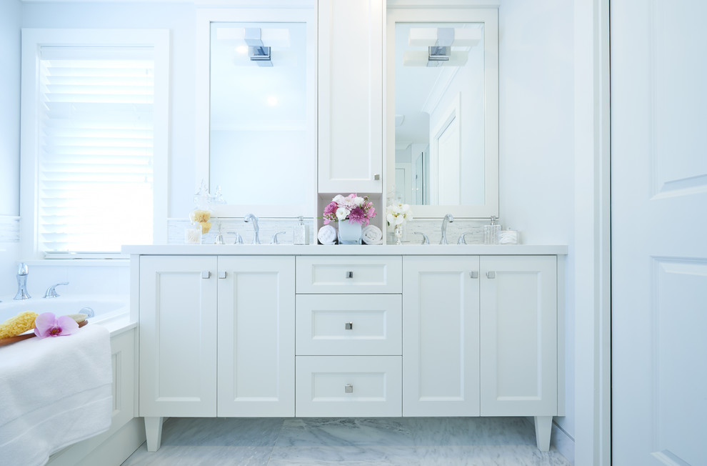 Exemple d'une salle de bain principale chic de taille moyenne avec un lavabo encastré, un placard à porte shaker, des portes de placard blanches, un plan de toilette en quartz modifié, une baignoire posée, un carrelage blanc, un mur bleu et un sol en marbre.