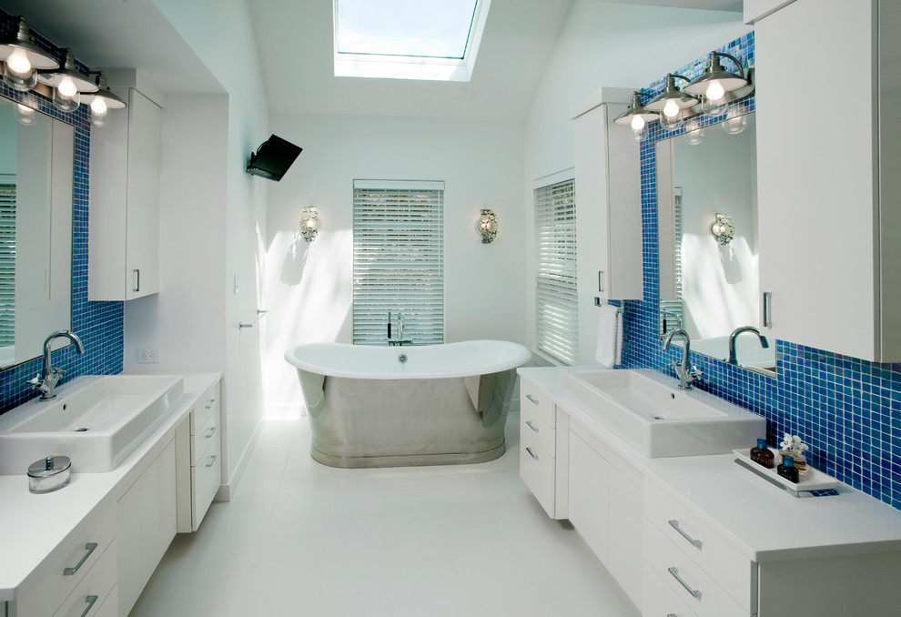 Источник вдохновения для домашнего уюта: большая главная ванная комната в стиле фьюжн с настольной раковиной, плоскими фасадами, белыми фасадами, столешницей из искусственного кварца, отдельно стоящей ванной, открытым душем, унитазом-моноблоком, синей плиткой, плиткой мозаикой, белыми стенами и полом из керамогранита