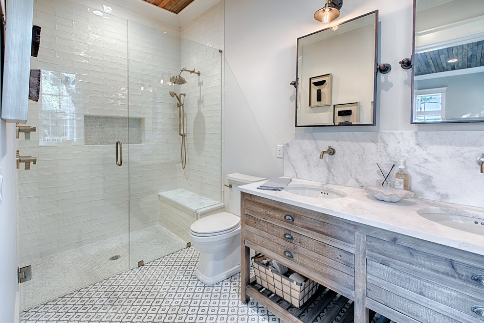 Lantlig inredning av ett badrum med dusch, med skåp i mellenmörkt trä, en kantlös dusch, vit kakel, vita väggar, ett undermonterad handfat, flerfärgat golv, dusch med gångjärnsdörr och släta luckor