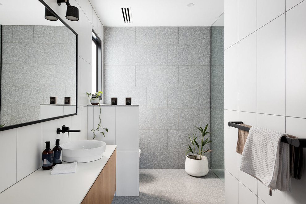 Bild på ett mellanstort vit vitt badrum för barn, med släta luckor, bruna skåp, en öppen dusch, grå kakel, stenkakel, vita väggar, betonggolv, ett konsol handfat, bänkskiva i kvarts, grått golv och med dusch som är öppen