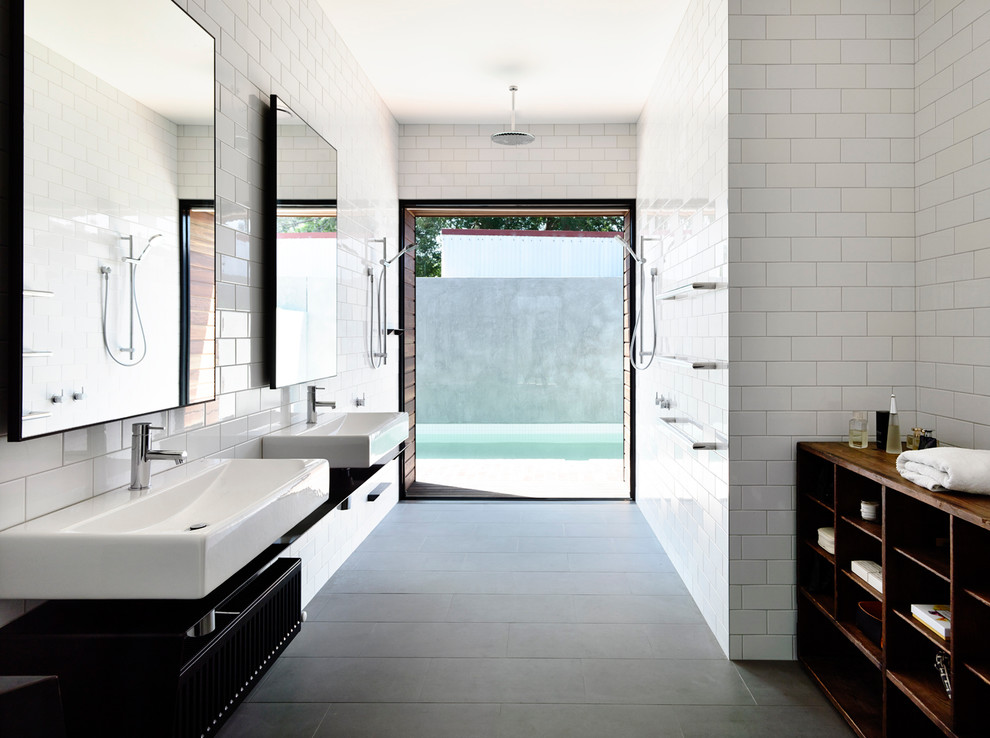 Inspiration för mellanstora moderna badrum, med ett väggmonterat handfat, vit kakel, tunnelbanekakel, öppna hyllor, svarta skåp, vita väggar, klinkergolv i keramik, bänkskiva i rostfritt stål, en kantlös dusch och grått golv