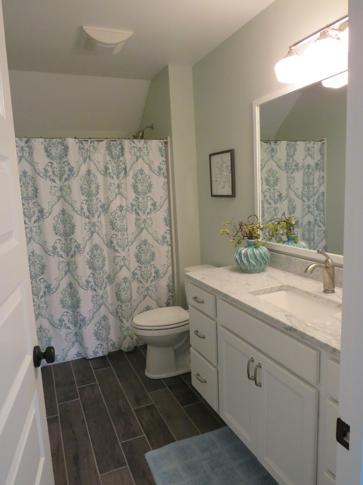 Lantlig inredning av ett mellanstort badrum med dusch, med vita skåp, gröna väggar, ett undermonterad handfat, marmorbänkskiva, luckor med infälld panel, ett hörnbadkar, en dusch/badkar-kombination, en toalettstol med separat cisternkåpa och linoleumgolv