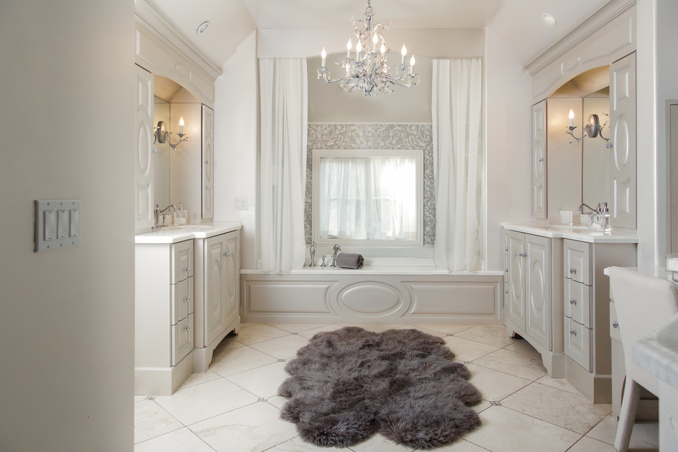 Photo of an expansive traditional ensuite bathroom in Other with an alcove bath, grey tiles, stone slabs, limestone flooring, a submerged sink, limestone worktops, beige floors, grey cabinets, white walls and raised-panel cabinets.