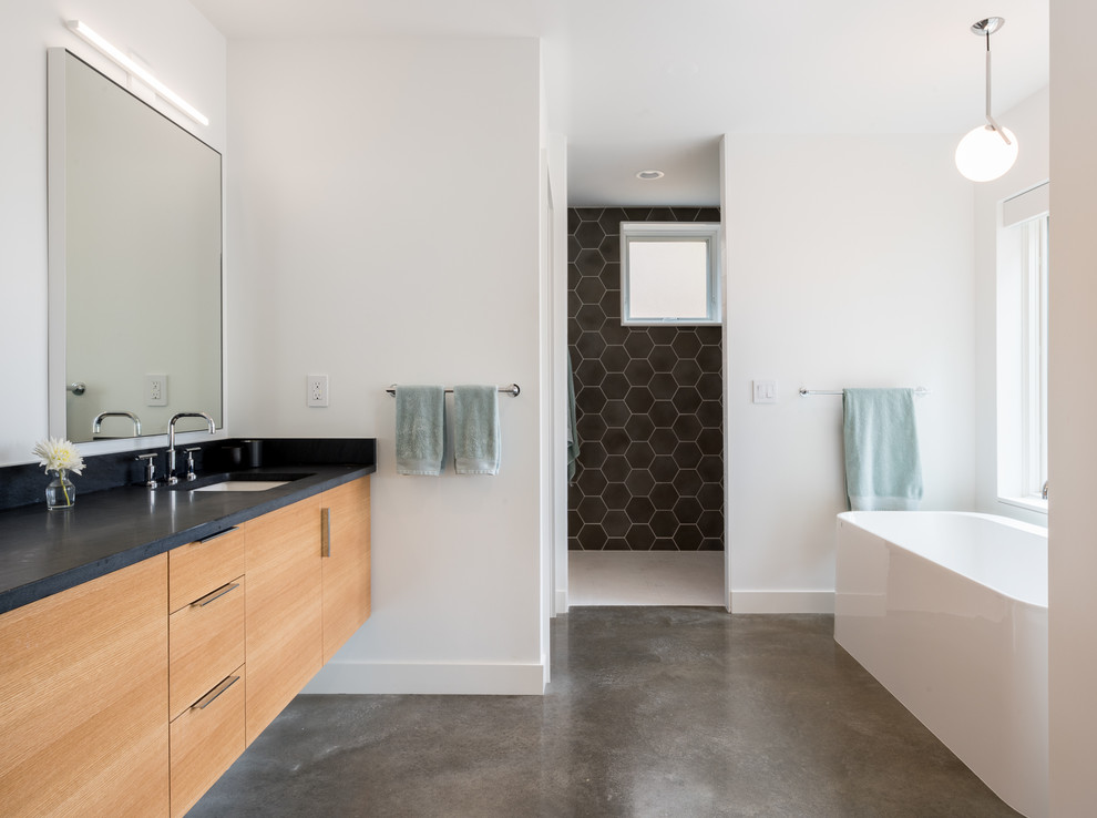 Idéer för funkis en-suite badrum, med släta luckor, skåp i ljust trä, ett fristående badkar, en öppen dusch, svart kakel, travertinkakel, betonggolv, ett undermonterad handfat och grått golv