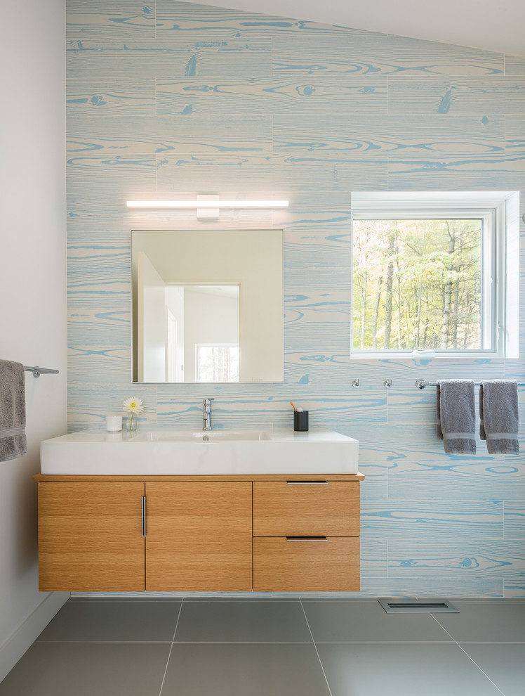 Idee per una stanza da bagno per bambini minimal con ante lisce, ante in legno chiaro, doccia aperta, piastrelle blu, piastrelle in travertino, pavimento in gres porcellanato, lavabo da incasso e pavimento grigio