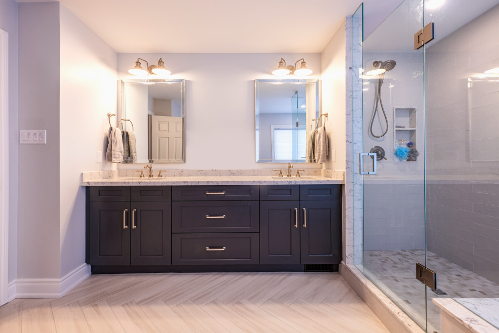 Photo of a medium sized classic ensuite bathroom in Toronto with shaker cabinets, blue cabinets, a freestanding bath, a corner shower, a one-piece toilet, white tiles, ceramic tiles, grey walls, cement flooring, a submerged sink, quartz worktops, grey floors, a hinged door and grey worktops.