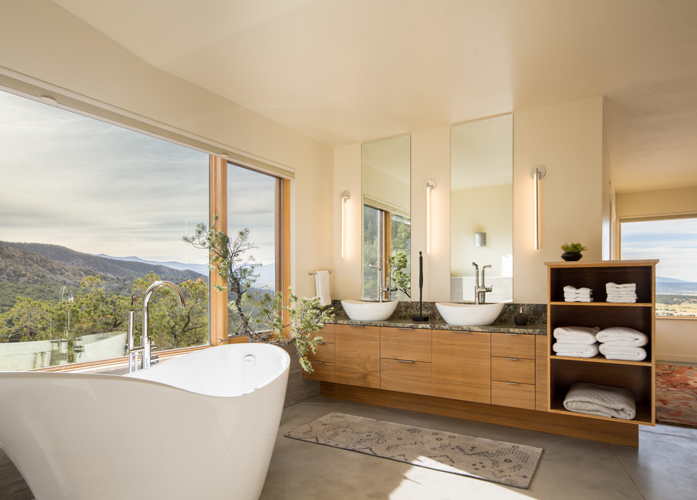 Inspiration pour une salle de bain principale design en bois brun avec un placard à porte plane, une baignoire indépendante, un mur beige, sol en béton ciré, une vasque, un sol gris et un plan de toilette multicolore.