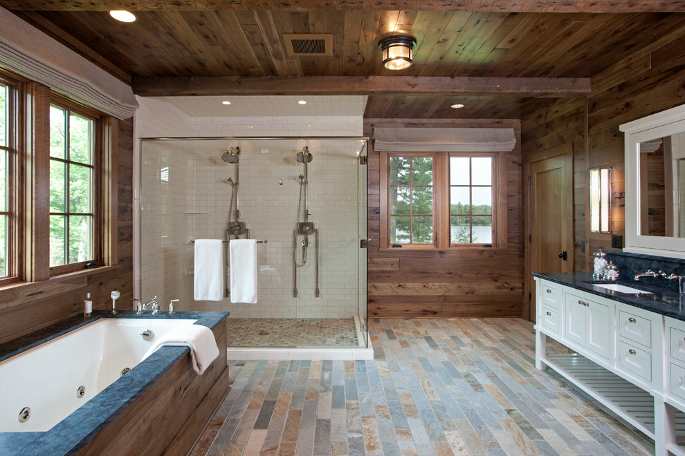 Inredning av ett rustikt en-suite badrum, med skåp i mellenmörkt trä, bänkskiva i kvartsit, ett platsbyggt badkar, en kantlös dusch, vit kakel, tunnelbanekakel, bruna väggar och skiffergolv