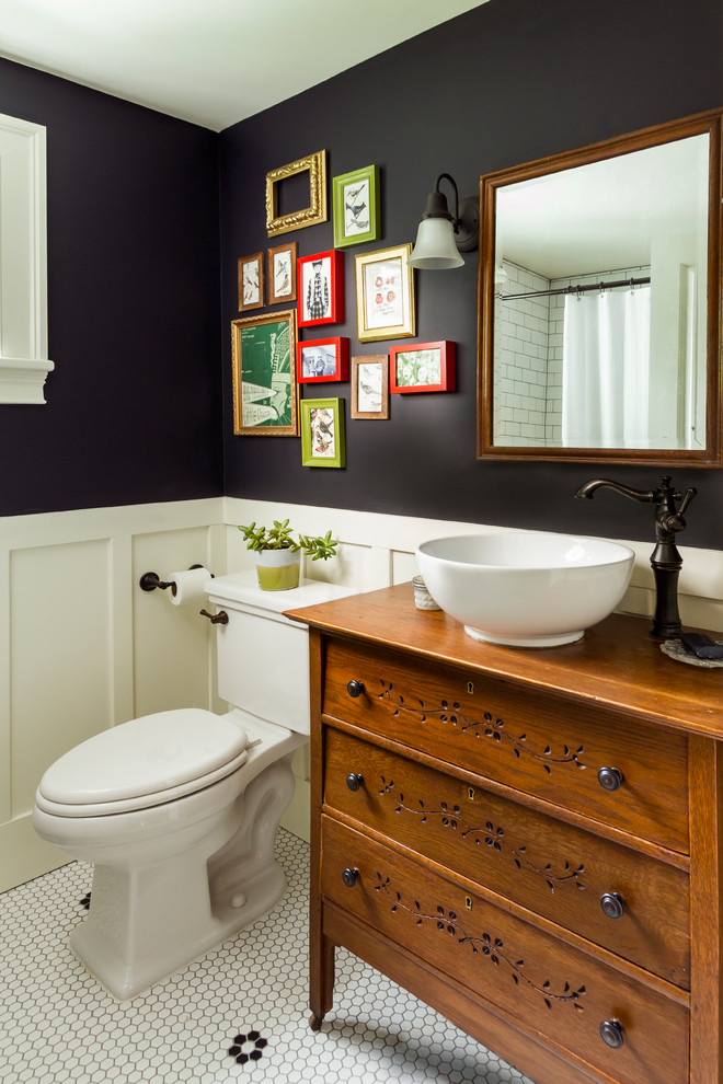 Foto på ett mellanstort lantligt brun badrum, med en toalettstol med separat cisternkåpa, skåp i mellenmörkt trä, svarta väggar, ett fristående handfat, träbänkskiva, flerfärgat golv och släta luckor
