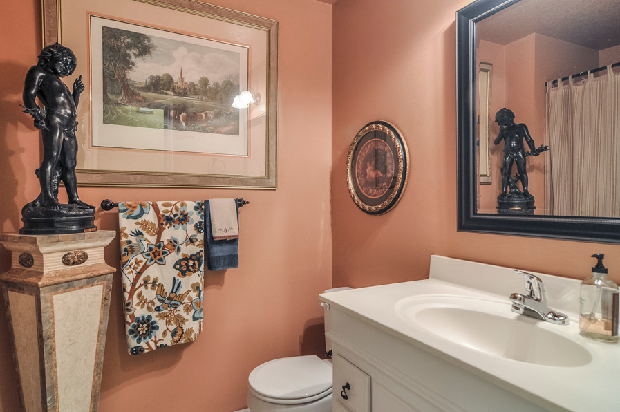 Exemple d'une salle de bain chic de taille moyenne avec un placard avec porte à panneau surélevé, des portes de placard blanches, WC séparés, un mur rose, un sol en carrelage de céramique, un lavabo intégré et un plan de toilette en surface solide.