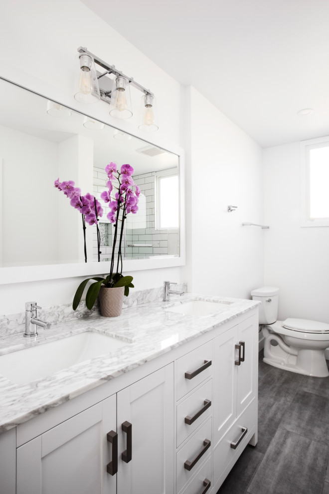 Example of a large transitional 3/4 gray floor and double-sink bathroom design in Los Angeles with shaker cabinets, white cabinets, a two-piece toilet, white walls, an undermount sink, gray countertops and a built-in vanity