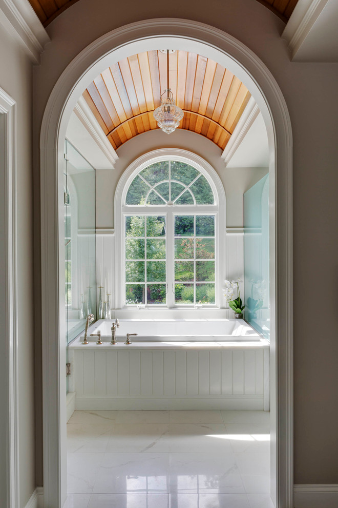 Inspiration pour une grande salle de bain principale traditionnelle avec des portes de placard blanches, une baignoire posée, un mur beige et un sol en marbre.