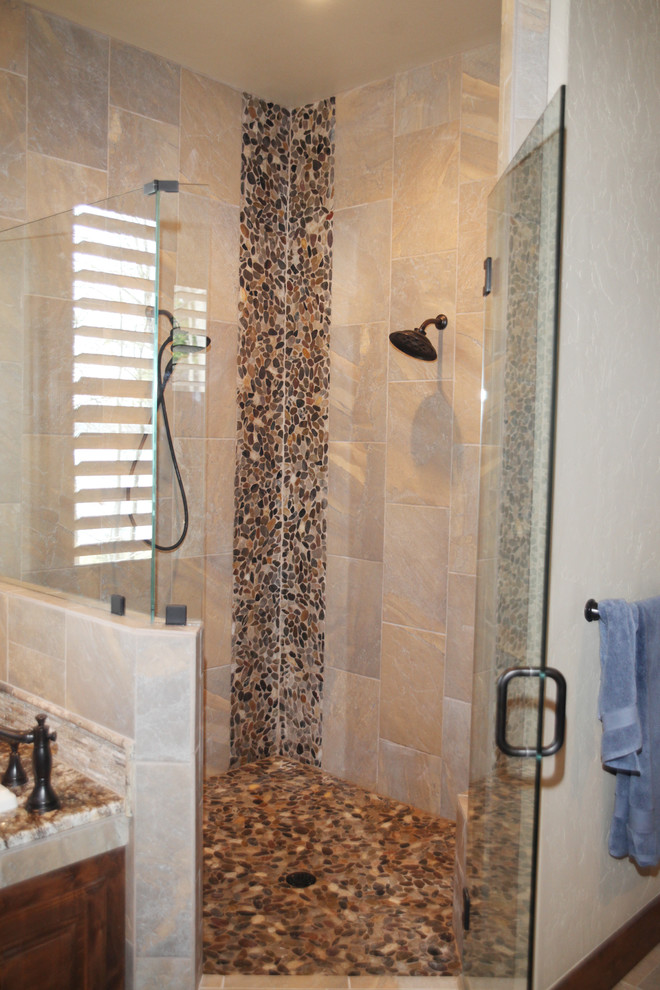 Cette photo montre une grande salle de bain principale chic en bois brun avec un placard avec porte à panneau surélevé, un carrelage beige, un mur beige, un sol en travertin, un lavabo encastré, un plan de toilette en granite, une douche d'angle et une plaque de galets.
