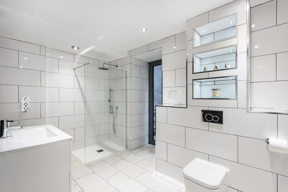 Cette photo montre une salle de bain tendance avec une douche ouverte, WC suspendus, un carrelage blanc, un mur blanc, un lavabo intégré et aucune cabine.