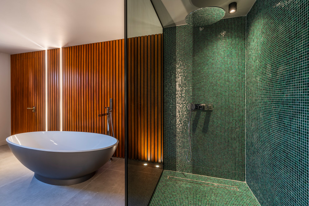 Inspiration for a contemporary bathroom in Dublin with a freestanding bath, green tiles, mosaic tiles, grey floors and wood walls.