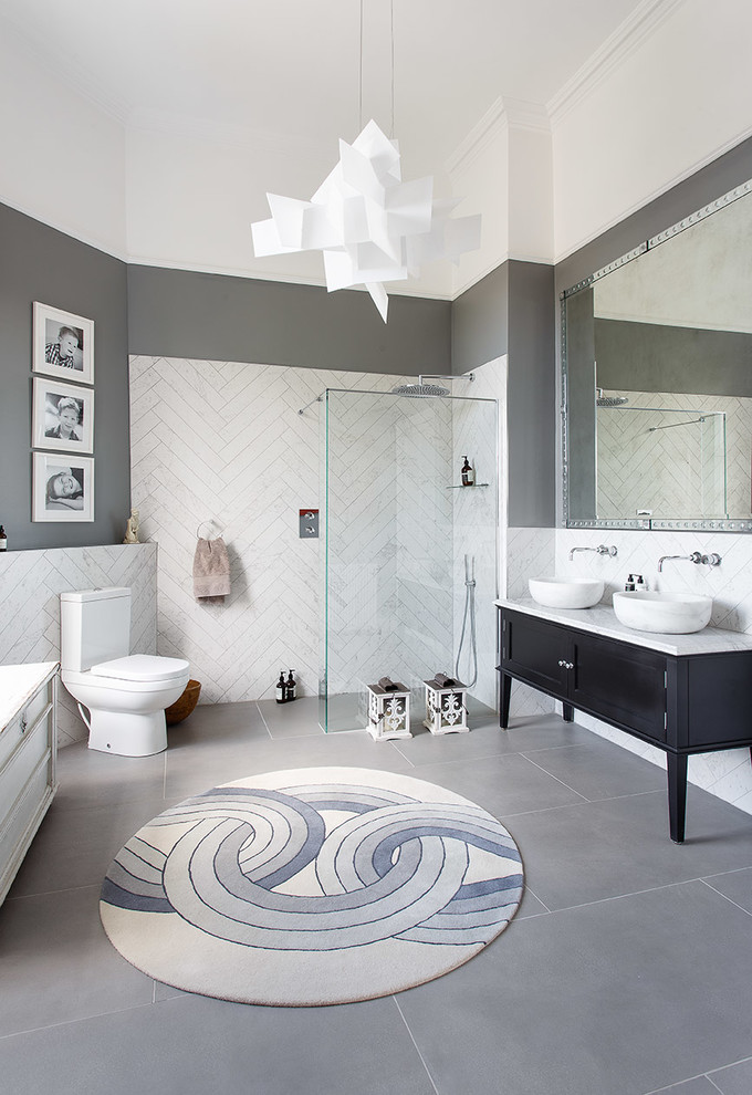 Cette image montre une salle de bain design avec des portes de placard noires, une douche à l'italienne, un carrelage blanc, un mur gris, une vasque, un sol gris, aucune cabine, un plan de toilette blanc et un placard à porte shaker.