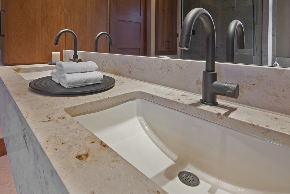 Aménagement d'une grande salle de bain principale contemporaine en bois brun avec un lavabo encastré, un placard avec porte à panneau encastré, un plan de toilette en calcaire, un carrelage beige, un carrelage de pierre, un mur beige et un sol en calcaire.