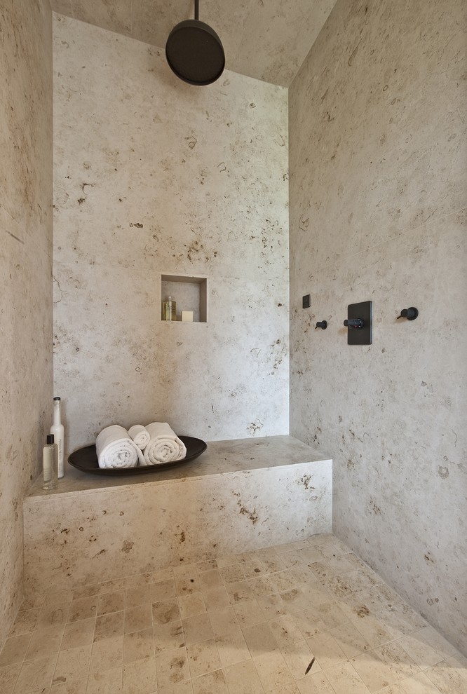 Cette photo montre une grande douche en alcôve principale tendance avec un carrelage beige, un sol en calcaire, du carrelage en travertin, un banc de douche et une niche.