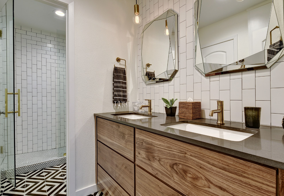 Foto på ett funkis badrum, med släta luckor, skåp i mellenmörkt trä, en dusch i en alkov, svart och vit kakel, vit kakel, tunnelbanekakel, vita väggar, ett undermonterad handfat och dusch med gångjärnsdörr