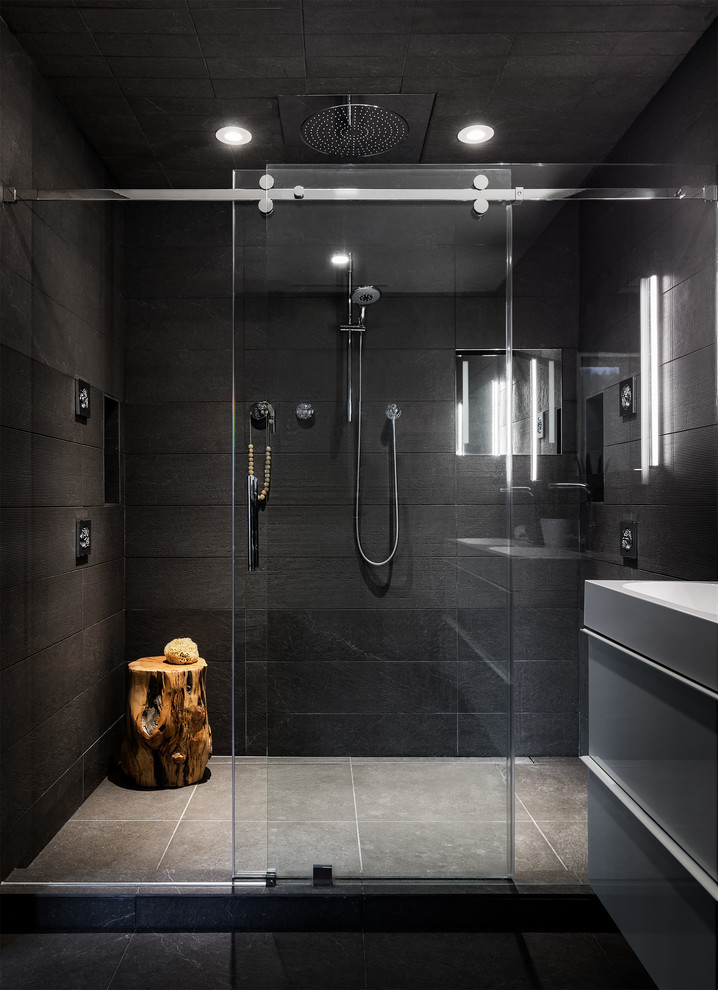 Design ideas for a medium sized contemporary ensuite bathroom in Boston with flat-panel cabinets, white cabinets, a double shower, a wall mounted toilet, grey tiles, porcelain tiles, grey walls, porcelain flooring, an integrated sink, engineered stone worktops, grey floors, a sliding door and white worktops.