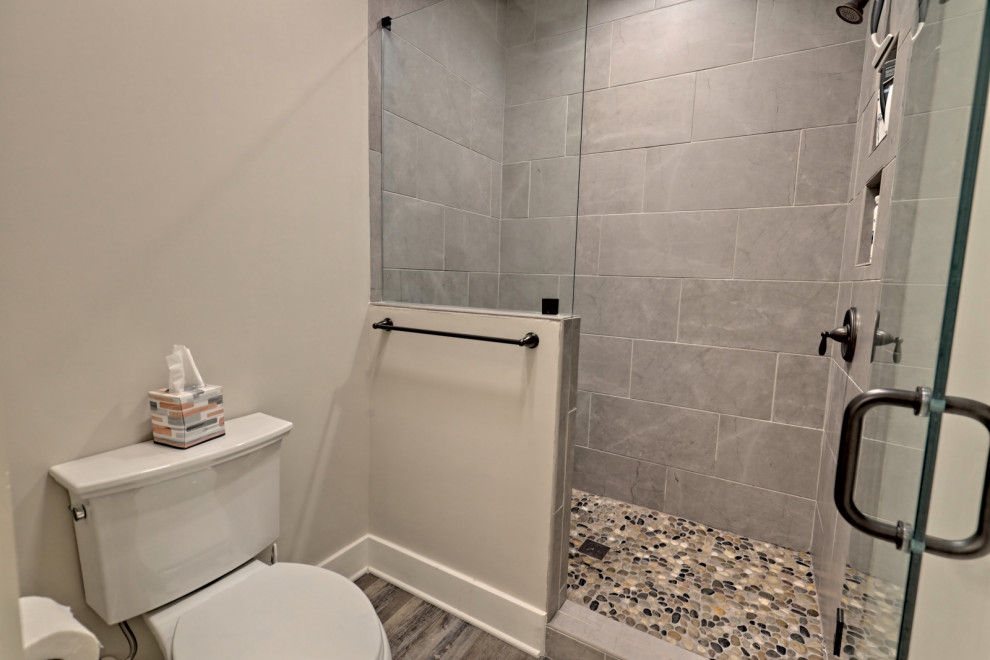 Exempel på ett stort amerikanskt flerfärgad flerfärgat badrum med dusch, med skåp i shakerstil, skåp i mörkt trä, ett badkar i en alkov, en dusch/badkar-kombination, en toalettstol med separat cisternkåpa, grå kakel, porslinskakel, grå väggar, vinylgolv, ett undermonterad handfat, granitbänkskiva, grått golv och dusch med gångjärnsdörr