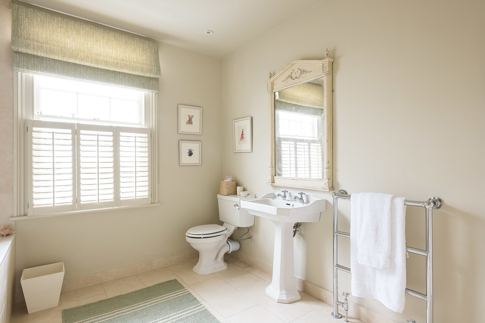Esempio di una stanza da bagno tradizionale con WC a due pezzi, pareti beige e lavabo a colonna