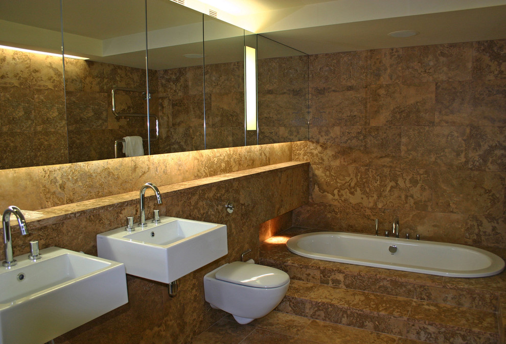 Cette image montre une salle de bain principale minimaliste de taille moyenne avec un lavabo suspendu, un placard à porte vitrée, un plan de toilette en marbre, une baignoire encastrée, WC suspendus, un mur orange, un sol en marbre et un carrelage marron.