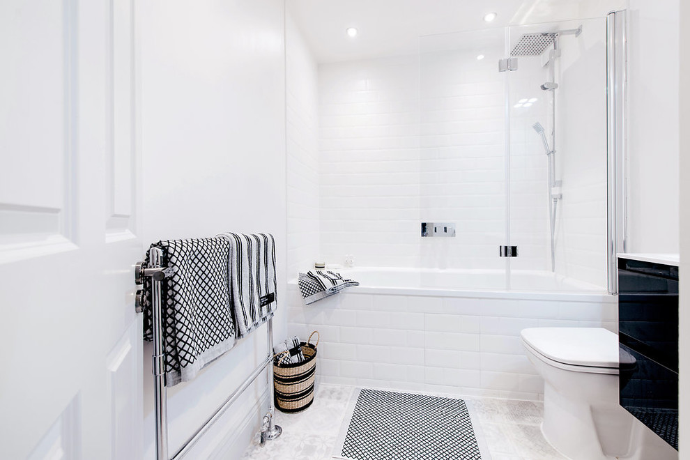 Design ideas for a small modern half tiled bathroom in Stockholm with a wall-mounted sink, grey cabinets, a built-in bath, a one-piece toilet, white tiles, white walls, ceramic flooring and a shower/bath combination.