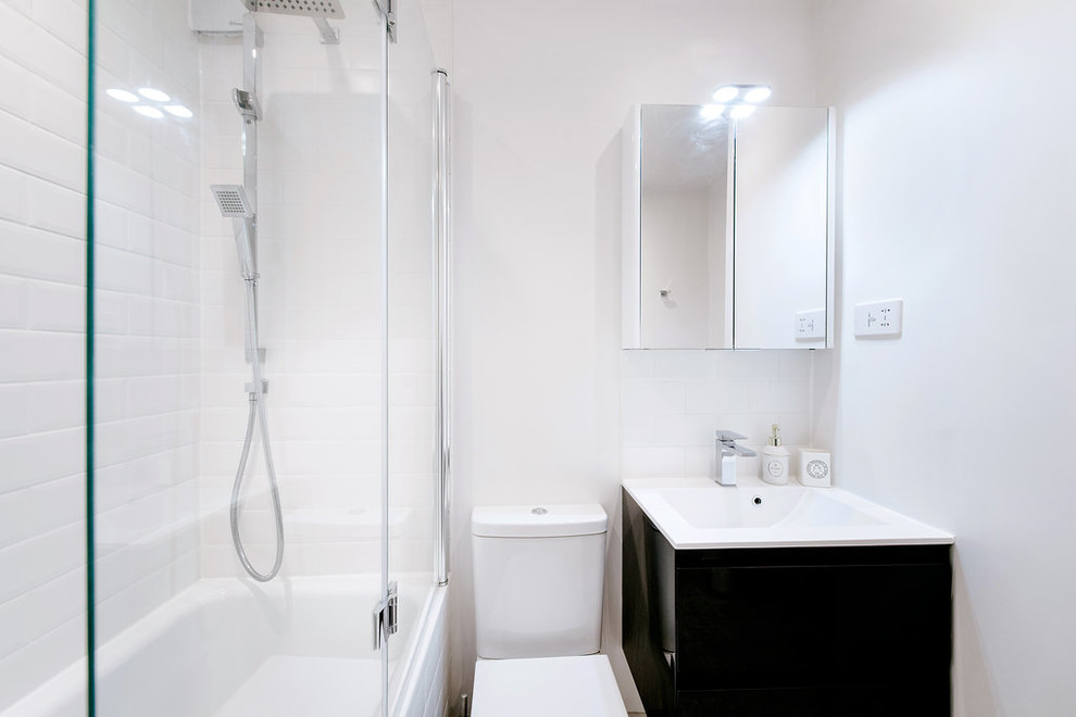 Foto di una piccola stanza da bagno moderna con lavabo sospeso, consolle stile comò, ante grigie, vasca da incasso, doccia a filo pavimento, WC monopezzo, piastrelle bianche, pareti bianche e pavimento con piastrelle in ceramica