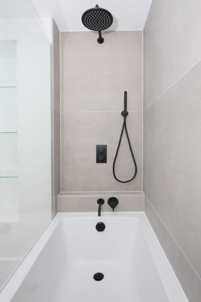 Photo of a small contemporary ensuite bathroom in London with an alcove bath, a shower/bath combination, a wall mounted toilet, grey tiles, porcelain tiles, white walls, porcelain flooring, a wall-mounted sink and beige floors.