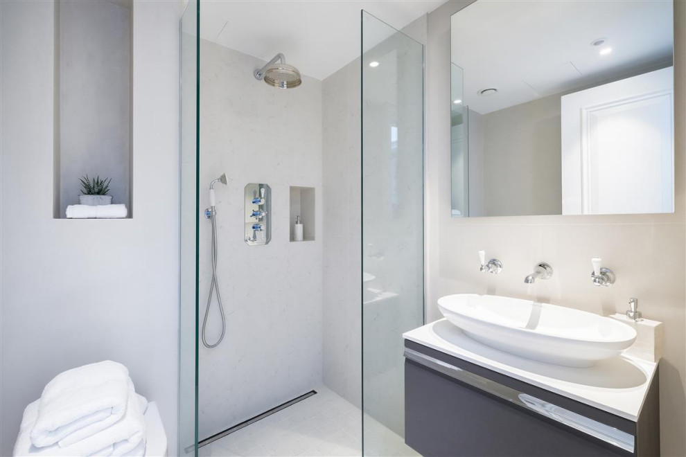 This is an example of a small contemporary shower room bathroom in London with grey cabinets, a corner shower, a wall mounted toilet, grey tiles, beige walls, a vessel sink, beige floors, white worktops and a single sink.
