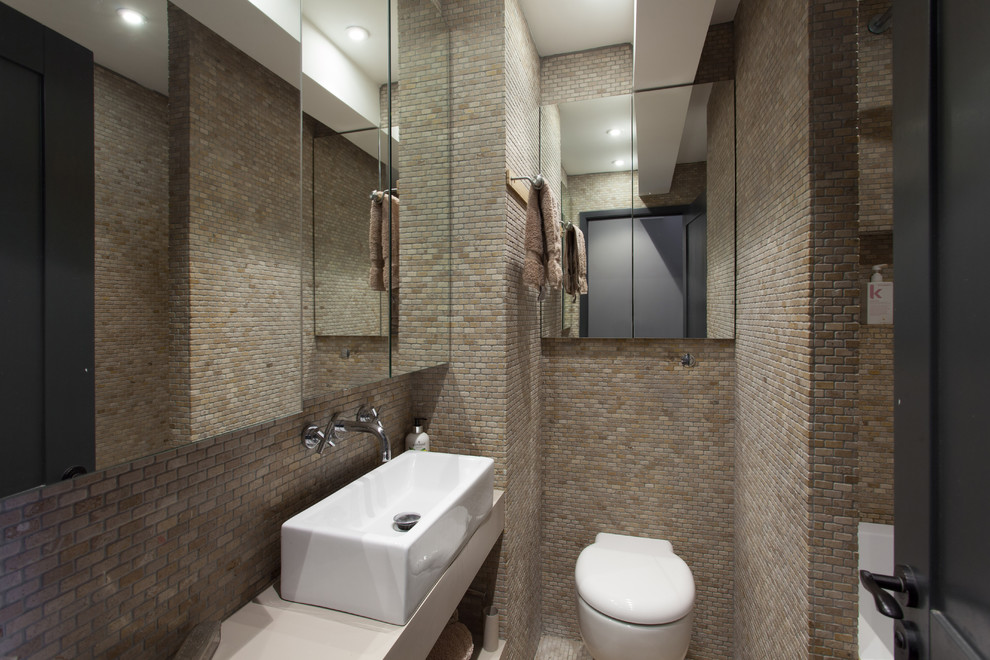Foto på ett litet funkis badrum med dusch, med öppna hyllor, en dusch i en alkov, en vägghängd toalettstol, brun kakel, mosaik, bruna väggar, mosaikgolv, ett fristående handfat och brunt golv