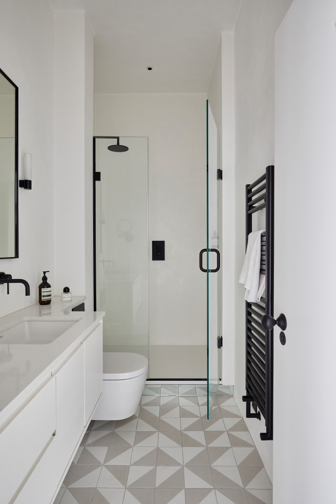 Small contemporary ensuite bathroom in London with flat-panel cabinets, white cabinets, a walk-in shower, a wall mounted toilet, ceramic flooring, engineered stone worktops, multi-coloured floors, a hinged door, a single sink and a floating vanity unit.