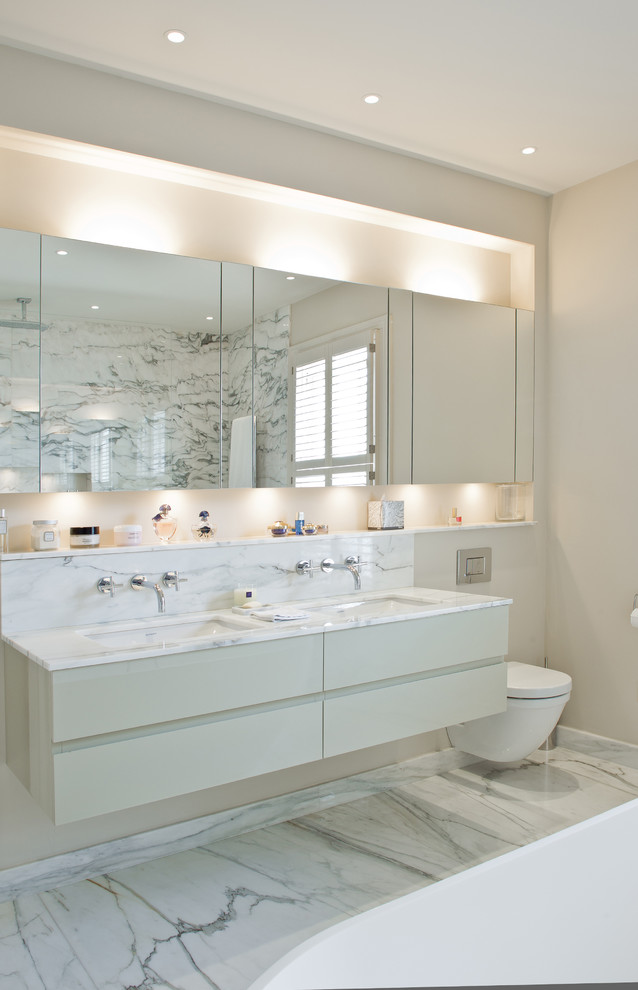 Inspiration pour une salle de bain design avec un placard à porte plane, des portes de placard blanches, WC suspendus, un mur beige et un lavabo encastré.