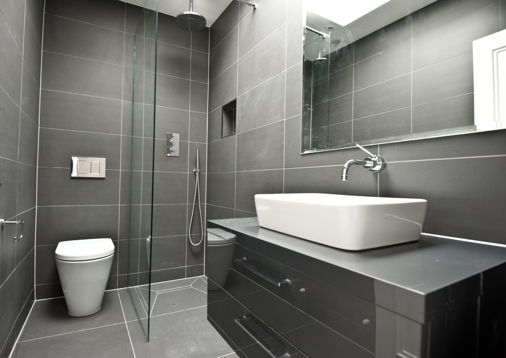 Example of a small trendy master gray tile and ceramic tile ceramic tile doorless shower design in London with gray cabinets, a one-piece toilet, gray walls, flat-panel cabinets and a vessel sink